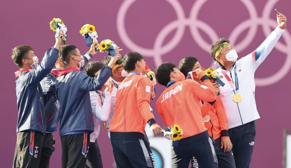 2022년 도쿄 올림픽에서 금메달을 딴 오진혁 선수가 휴대폰을 꺼내 들고대만 및 동메달의 일본 선수들을 1등 단상으로 초대해 함께 셀카를 찍고 있다./ 연합