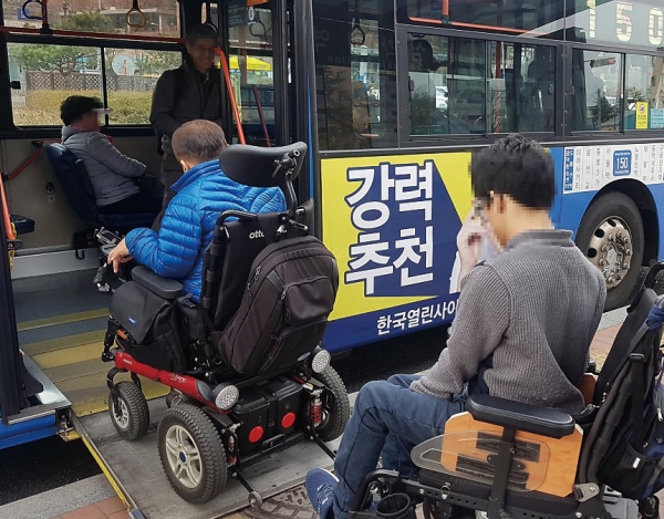 휠체어를 탄채 시내버스에 오르는 장애인들.